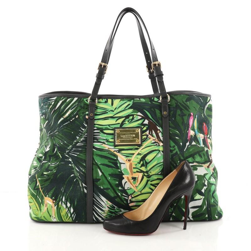 This authentic Louis Vuitton Ailleurs Cabas Limited Edition Printed Canvas GM is a marvelous tote, ideal for everyday use. Crafted from green printed canvas, this chic and fun tote features tropical jungle scene print, dual adjustable flat leather