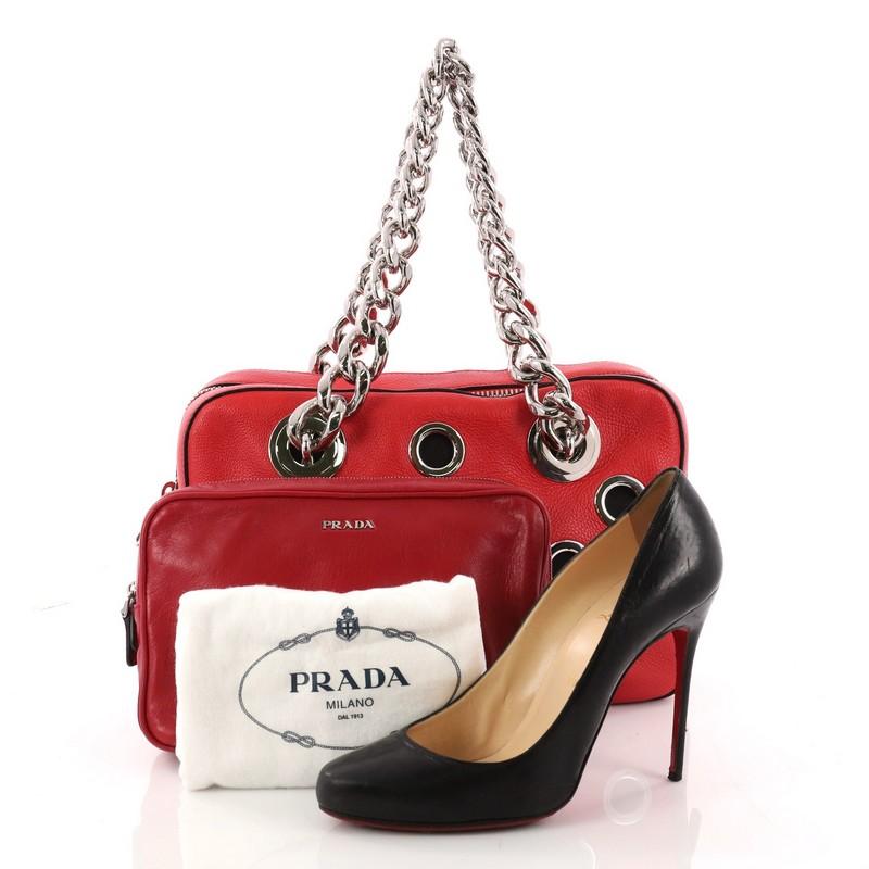 This authentic Prada Grommet Chain Shoulder Bag Vitello Daino Medium is a gorgeous shoulder bag perfect for your day or evening looks. Crafted from red vitello daino leather, this chic bag features dual chunky silver chain straps, large grommets