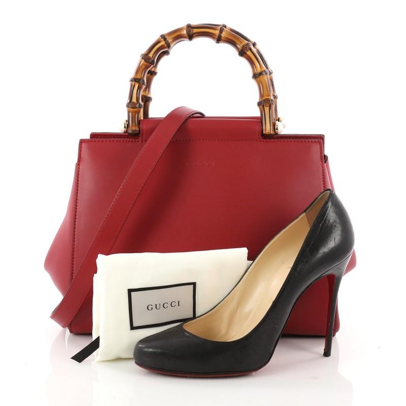 This authentic Gucci Nymphaea Tote Leather Small is a stylish bag perfect for the modern fashionista. Crafted in red leather, this gorgeous bag features a leather shoulder strap, bamboo handles with pearls, and gold-tone hardware accents. Its snap
