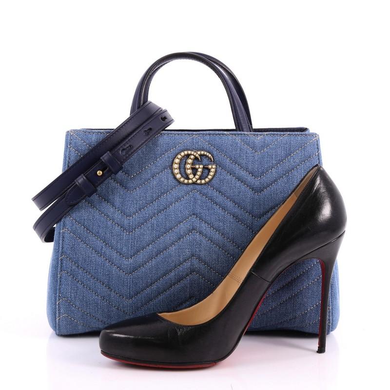 This authentic Gucci Pearly GG Marmont Tote Matelasse Denim Small balances understated versatility with glamorous flair. Crafted from blue denim in chevron matelasse design, this stylish bag features dual top leather handles, interlocking pearl