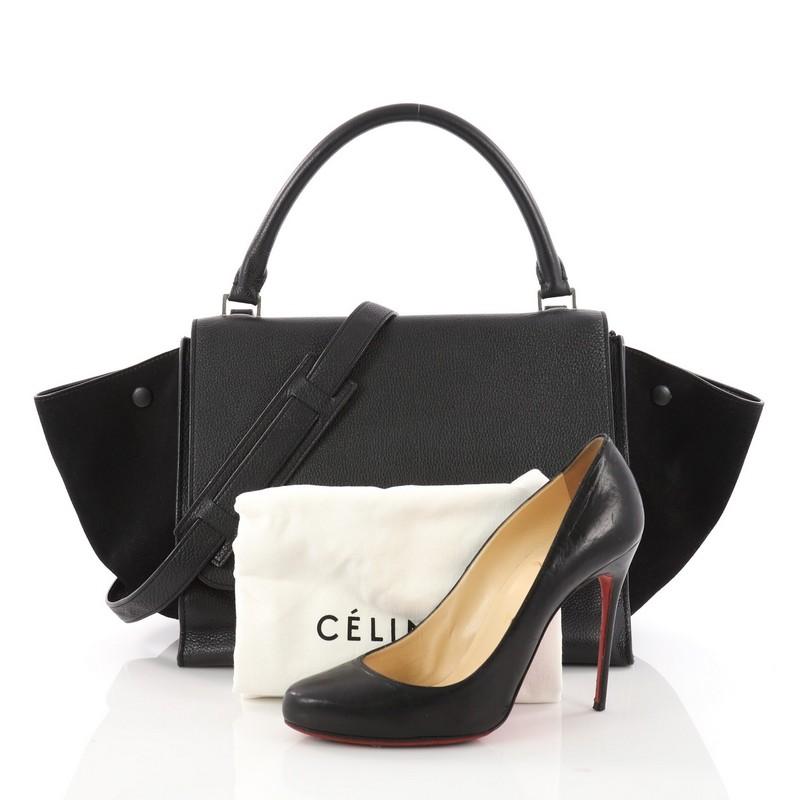 This authentic Celine Trapeze Handbag Leather Medium is a modern minimalist design with a playful twist in an array of subdued colors. Crafted from black leather with black suede wings, this popular bag features exterior back zip pocket, side snap