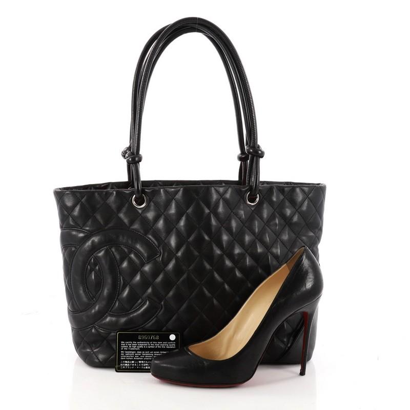This authentic Chanel Cambon Tote Quilted Leather Large is finely crafted from black diamond quilted leather. This tote displays a large black leather interlocking CC side logo, dual-rolled black leather handles with knotted ends, protective base