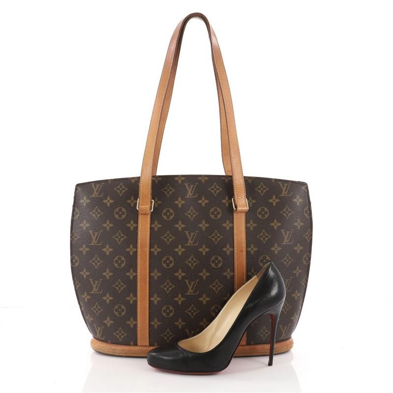 This authentic Louis Vuitton Babylone Handbag Monogram Canvas is a stylish and durable tote that is ideal for everyday use. Crafted from brown monogram coated canvas, this bag features natural vachetta cowhide leather straps and trims, gold-tone