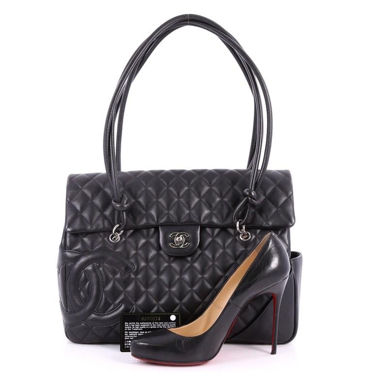 This authentic hard-to-find Chanel Cambon Flap Tote Quilted Leather Large is a stylish and functional accessory perfect for daily excursions. Crafted in black quilted leather, this tall tote features tall handles with knotted ends, signature CC logo