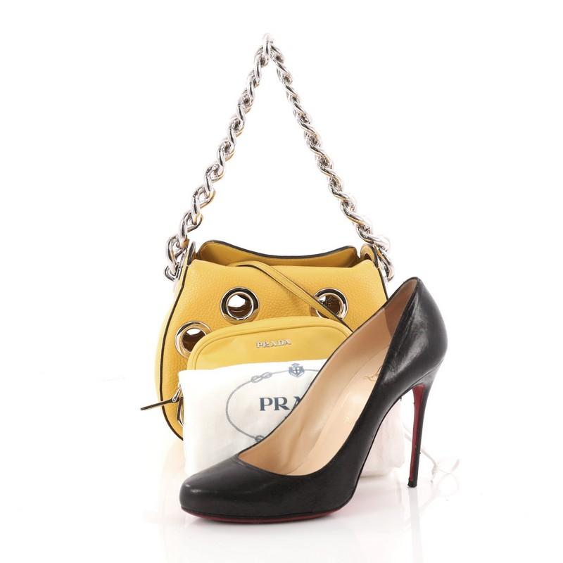 This authentic Prada Grommet Chain Hobo Vitello Daino Small is a gorgeous shoulder bag perfect for your day or evening looks. Crafted from yellow vitello daino leather, this chic bag features chunky silver chain shoulder strap, large grommets