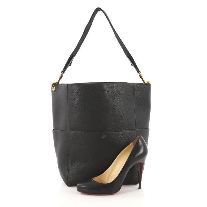 This authentic Celine Sangle Seau Handbag Goatskin Large balances a simple yet luxurious style, perfect for the on-the-go woman. Crafted from black goatskin, this minimalist bucket bag features a detachable canvas shoulder strap, multiple exterior