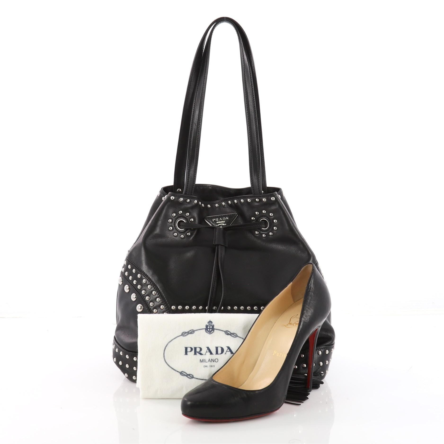 This authentic Prada Bucket Bag Studded Soft Calfskin Large is a classic bucket bag with modern minimalist touches that we love. Crafted in black studded soft calfskin leather, this bag features flat leather shoulder strap, an adjustable leather