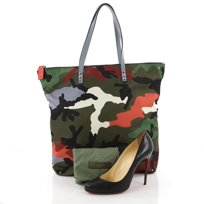 This authentic Valentino Rockstud Open Reversible Convertible Tote Camo Nylon Medium is the perfect daily bag for an on-the-go fashionista. Crafted in green and multicolor Camo Nylon, this chic stand-out tote features the brand's iconic pyramid