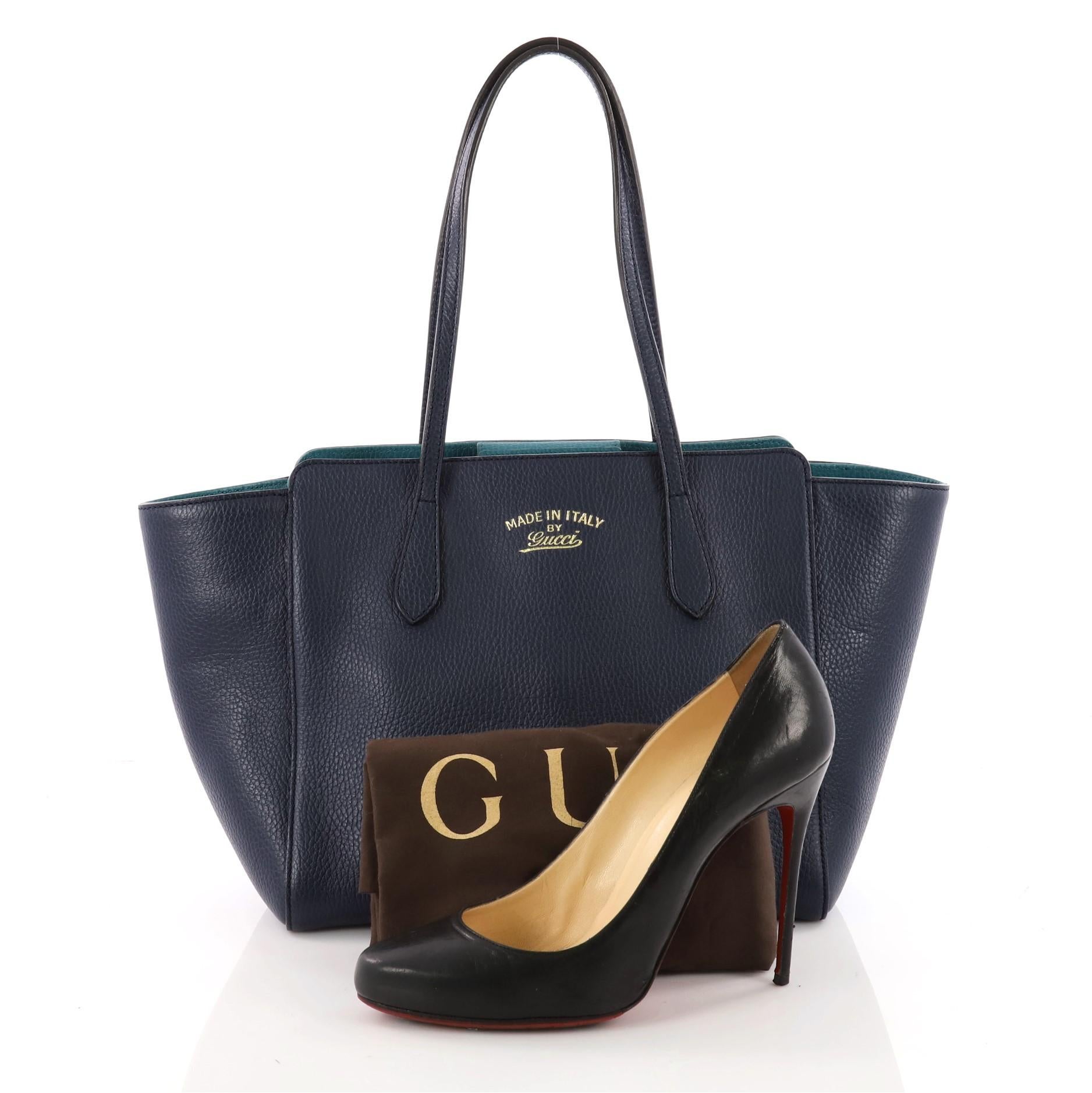 This authentic Gucci Swing Tote Leather Small is modern and sophisticated in design. Crafted in blue leather, this elegant tote features tall dual-slim handles, Gucci stamped logo at the front, expanded wing silhouette, and gold-tone hardware