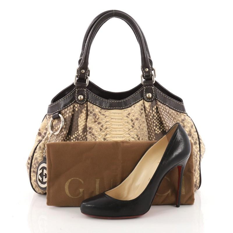 This authentic Gucci Sukey Tote Python Medium is a chic tote ideal for your everyday wear. Crafted from genuine brown python skin, this pleated tote features dual-rolled leather top handles, brown leather trims, side snap buttons, and gold-tone