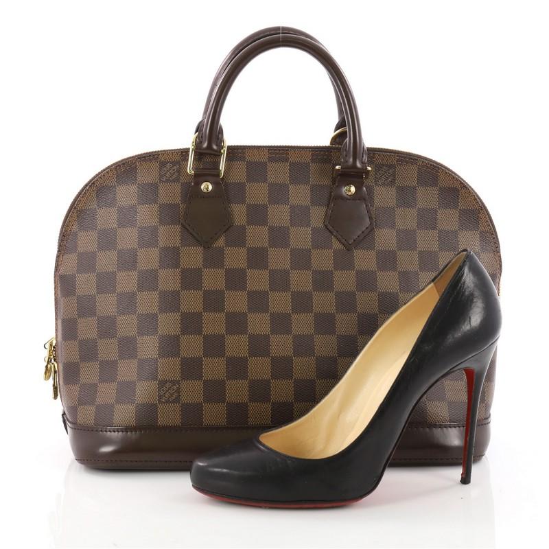 This authentic Louis Vuitton Vintage Alma Handbag Damier PM is an elegant spin on a classic style that is perfect for all seasons. Crafted from Louis Vuitton's damier ebene coated canvas, this iconic dome-shaped satchel features dual-rolled handles,
