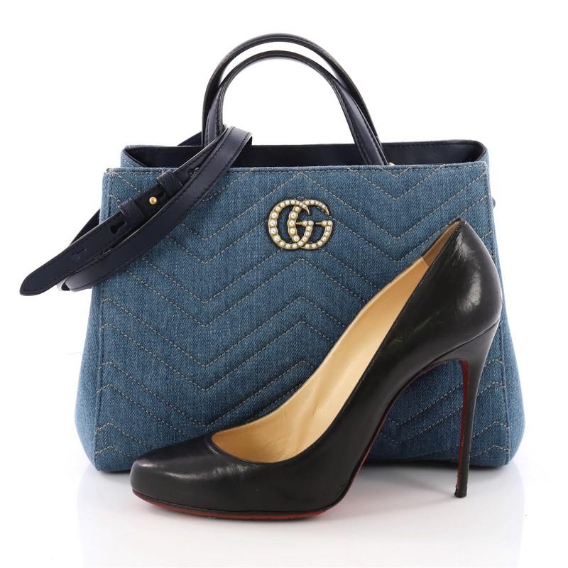 This authentic Gucci Pearly GG Marmont Tote Matelasse Denim Small balances understated versatility with glamorous flair. Crafted from blue denim in chevron matelasse design, this stylish bag features dual top leather handles, interlocking pearl