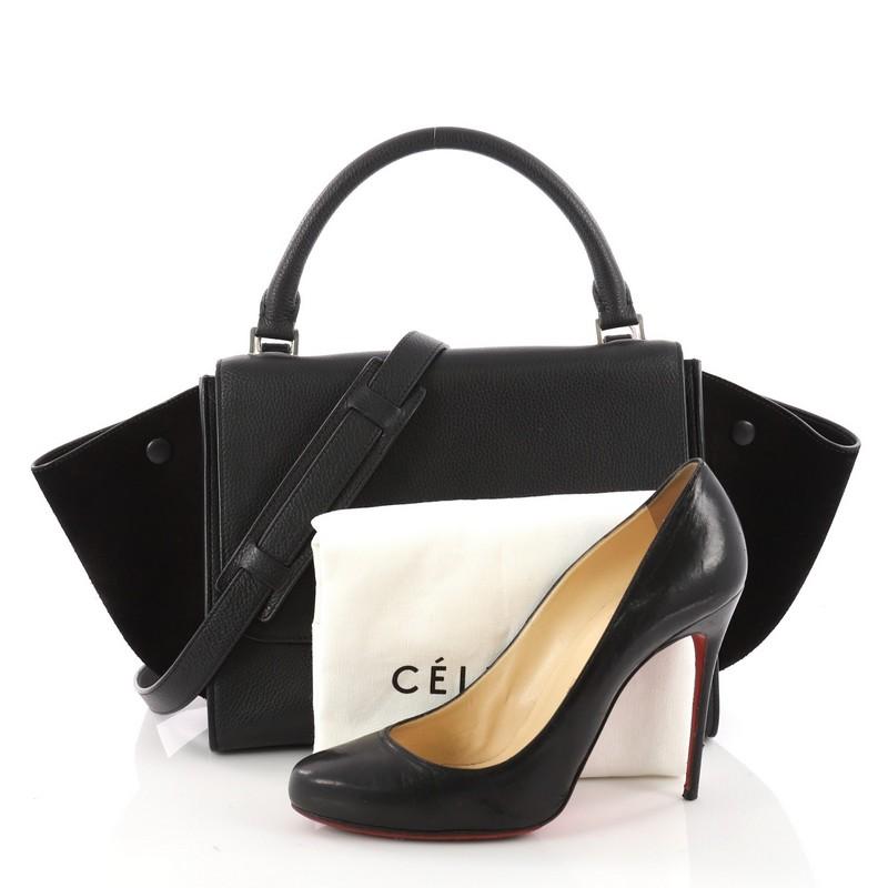 This authentic Celine Trapeze Handbag Leather Small is a modern minimalist design with a playful twist. Crafted from black leather with suede wings, this classic bag features rolled top handle, exterior back zip pocket, expanded side wings with snap