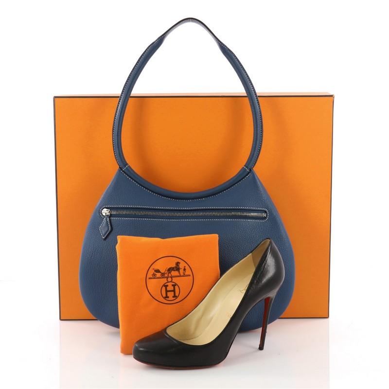 This authentic Hermes Cacahuete Handbag Clemence is a fabulous addition to your Hermes collection. Crafted in blue clemence leather, this wonderful bag features a rolled leather handle, pleated bottom and palladium-tone hardware accents. Its zip