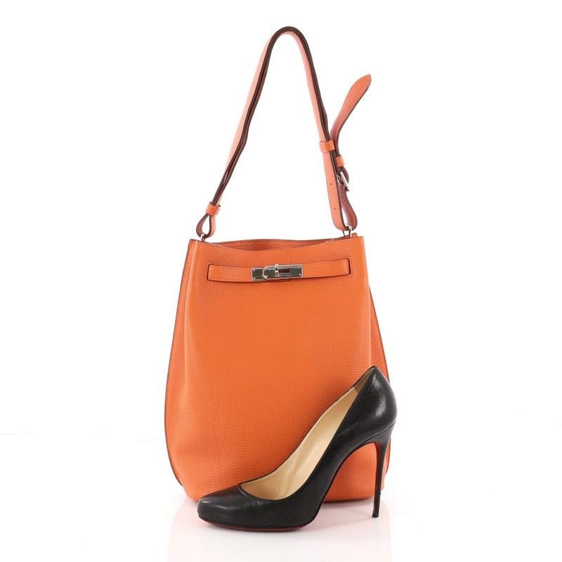 This authentic Hermes So Kelly Handbag Togo 22 first released in 2008 is an updated and modern reinterpretation of the Kelly Sport taking its distinct look to Hermes' classic Kelly design. Crafted in orange togo leather, this luxurious hobo-inspired