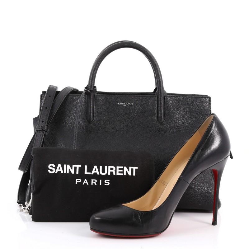 This authentic Saint Laurent Rive Gauche Cabas Leather Small is a sleek yet elegant bag synonymous with the brand's classic aesthetic. Crafted from black leather, this tote features a Saint Laurent stamp signature at the front, dual-rolled leather