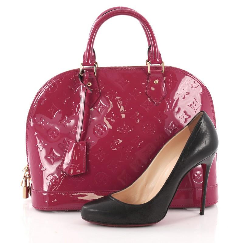 This authentic Louis Vuitton Alma Handbag Monogram Vernis PM is a fresh and elegant spin on a classic style that is perfect for all seasons. Crafted from Louis Vuitton's dark pink monogram vernis leather, this dome-shaped satchel features