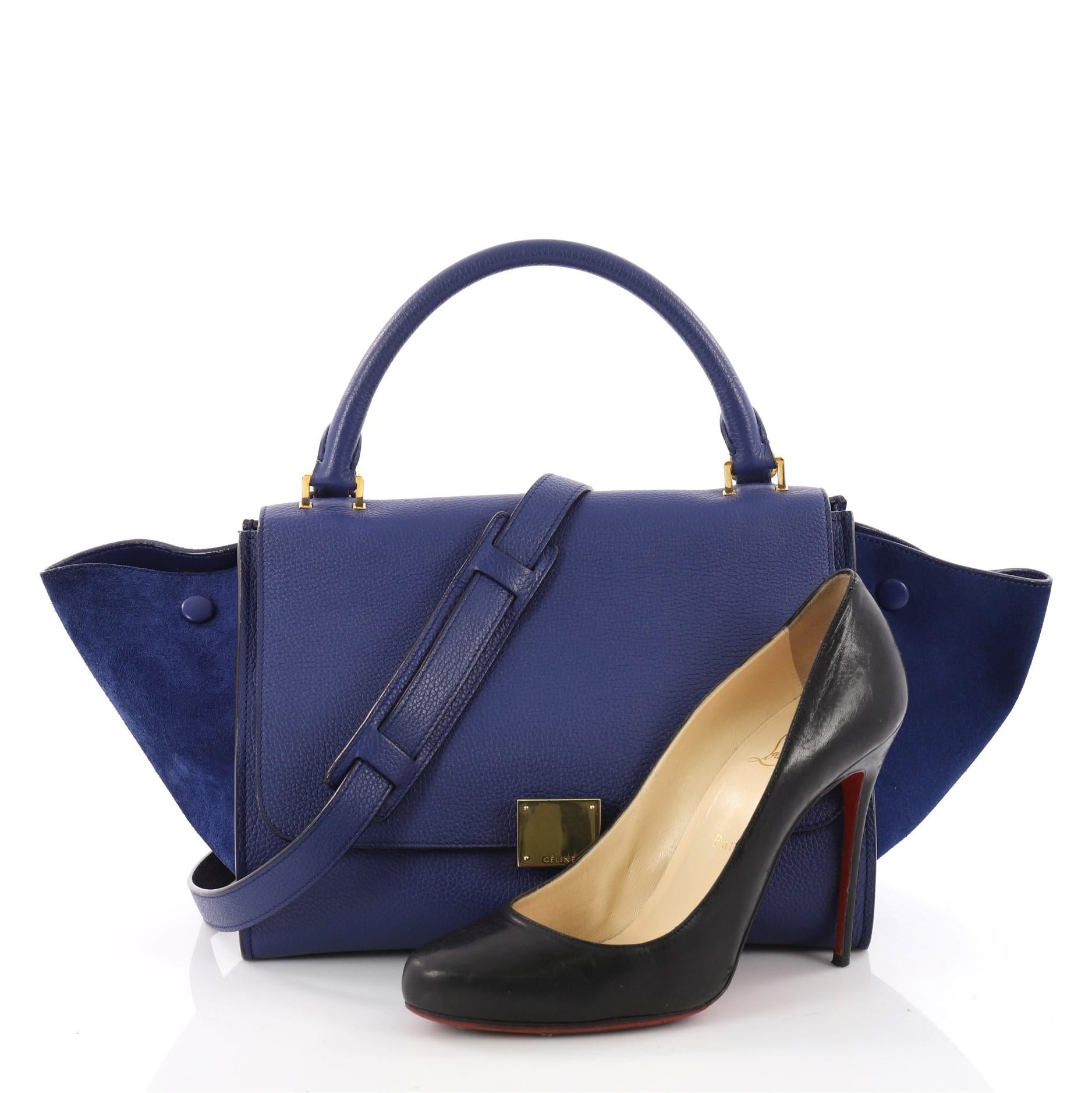 This authentic Celine Trapeze Handbag Leather Small is modern and minimalist in design. Crafted from blue leather and suede wings, this popular bag features exterior back zip pocket, side snap closures, top looped handle and gold-tone hardware