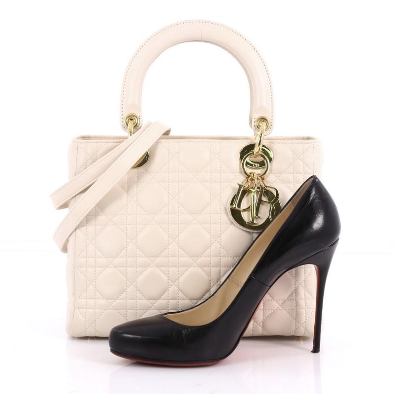 This authentic Christian Dior Lady Dior Handbag Cannage Quilt Lambskin Medium is an elegant classic bag that every fashionista needs in her wardrobe. Crafted from ivory white lambskin leather in Dior's iconic cannage quilting, this boxy bag features