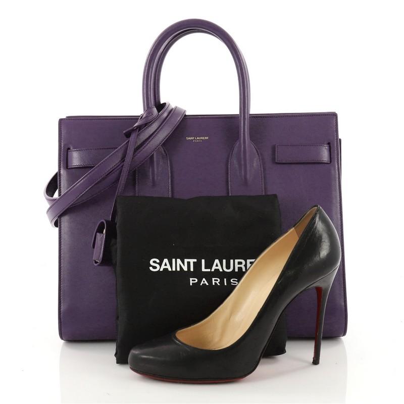 This authentic Saint Laurent Sac de Jour Handbag Leather Small is a sleek yet elegant bag synonymous with the brand's classic aesthetic. Crafted from purple leather, this sought-after tote features a gold Saint Laurent embossed signature at the