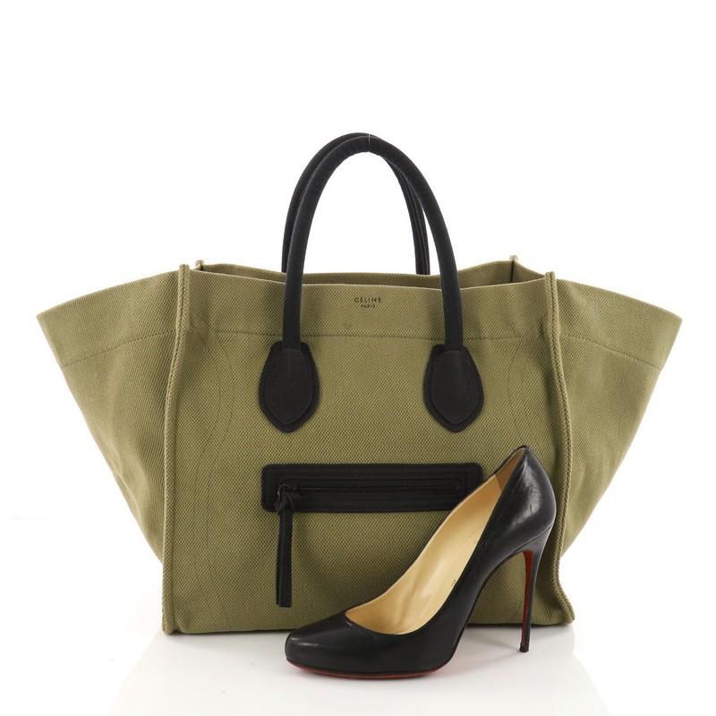 This authentic Celine Phantom Handbag Canvas Large is one of the most sought-after bags beloved by many fashionistas. Crafted from green canvas, this minimalist tote features dual-rolled handles, an exterior front pocket, protective base studs,