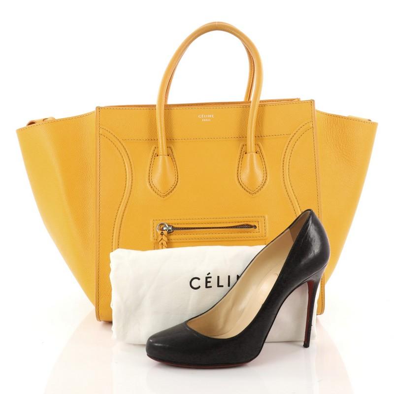 This authentic Celine Phantom Handbag Grainy Leather Medium is one of the most sought-after bags beloved by fashionistas. Crafted from yellow grainy leather, this minimalist tote features dual-rolled handles, an exterior front pocket, protective
