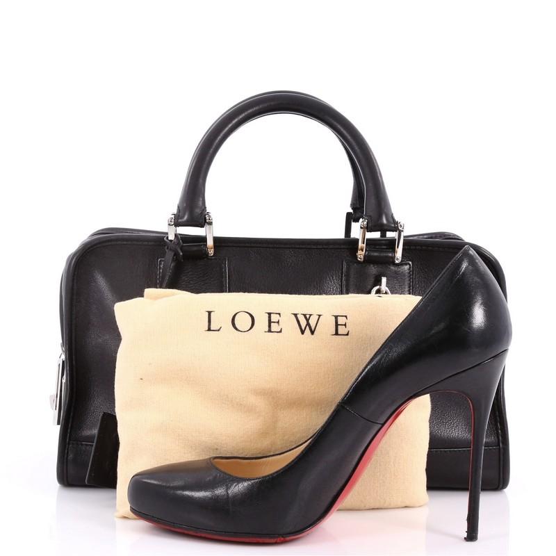 This authentic Loewe Amazona Bag Leather 28 is a perfect minimalist handbag for on-the-go fashionista. Crafted in black leather, this bag features dual-rolled leather handles, embossed logo at front, and silver-tone hardware accents. Its zip closure