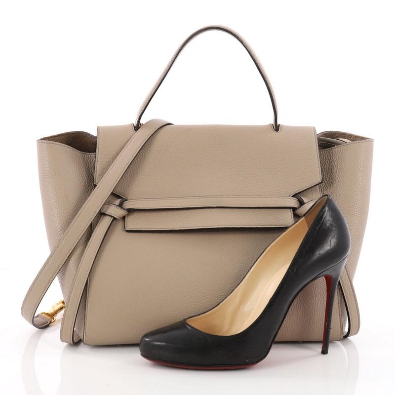 This authentic Celine Belt Bag Grainy Leather Mini is sure to make a statement. Crafted from beige grainy leather, this bold and beautiful bag features expanded wings, looped single top handle, top flap slide closure, knotted ties, zipper pocket at