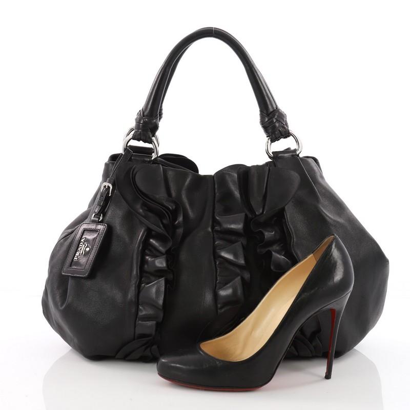 This authentic Prada Ruffle Shoulder Bag Leather Large is a marvelous hobo for your day or evening looks. Crafted from black leather, this stylish bag features dual looping reinforced leather handles, ruffled and pleated accents and silver-tone