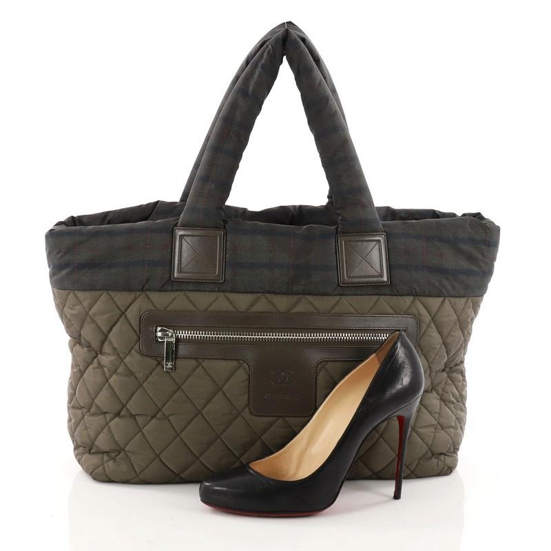 This authentic Chanel Coco Cocoon Zipped Tote Quilted Printed Nylon Medium is a highly sought after piece from Lagerfeld's fun and chic Coco Cocoon line. Crafted from green quilted printed and solid nylon, this sporty-chic tote features dual padded