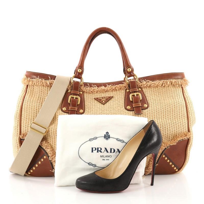 This authentic Prada Paglia Tote Raffia with Leather Large is a fabulous bag for every day with the luxe appeal. Crafted in raffia with brown leather and fringed raffia trims, this uniquely structured and beautifully made bag features dual-rolled