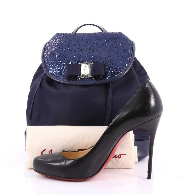 This authentic Salvatore Ferragamo Bow Flap Backpack Nylon with Sequins and Leather Medium is a chic and feminine backpack that compliments any casual look. Crafted from navy blue nylon with sequins and leather, this stand-out, stylish backpack