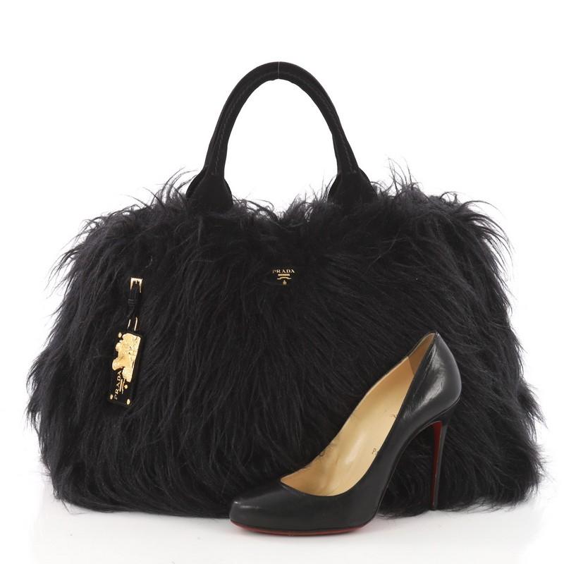 This authentic Prada Eco Kidassia Tote Faux Fur is a luxurious garden tote perfect for day to evening. Crafted in plush layers of nero black faux fur, this unique bag features dual-rolled handles, side snap buttons, Prada logo and gold-tone hardware