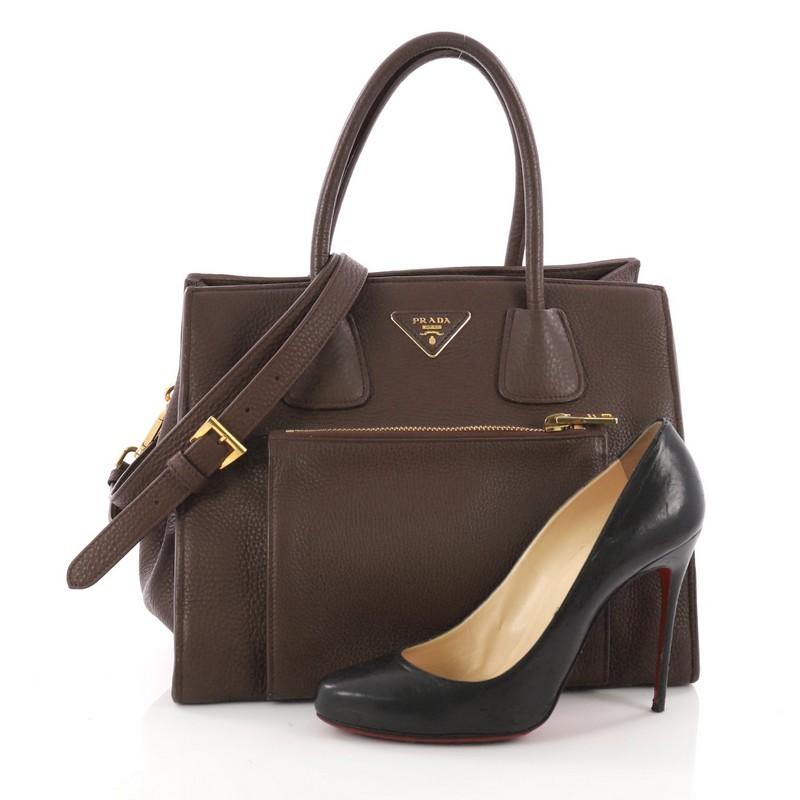 This authentic Prada Front Pocket Wing Convertible Tote Vitello Daino exudes a stylish and industrial design made for everyday excursions. Crafted from brown vitello daino leather, this tote features dual-rolled leather handles, exterior front zip