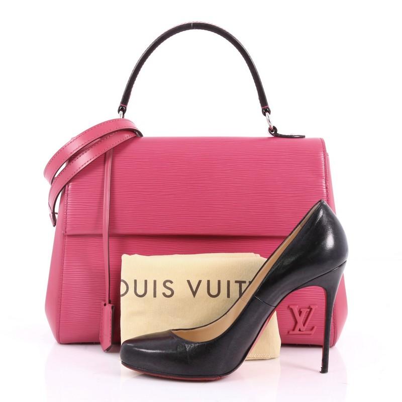 This authentic Louis Vuitton Cluny Top Handle Bag Epi Leather MM is a chic and sophisticated everyday bag. Crafted from pink epi leather with smooth leather panels, this timeless bag features short flat top handle, side snap buttons, LV logo at
