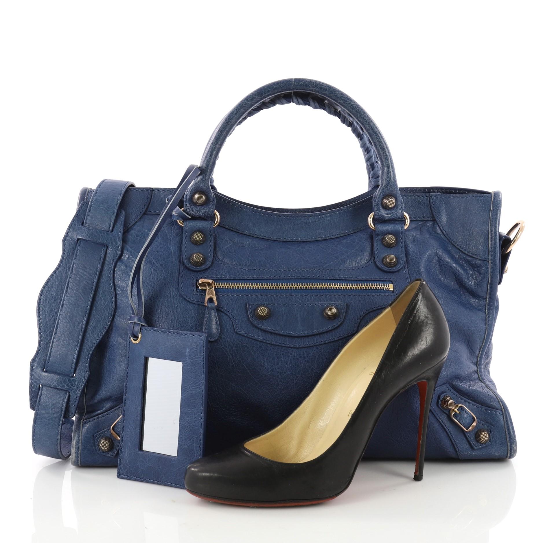 This authentic Balenciaga City Giant Studs Handbag Leather Medium is for the on-the-go fashionista. Constructed from blue leather, this popular bag features dual braided woven tall handles, exterior front zip pocket, iconic Balenciaga giant studs