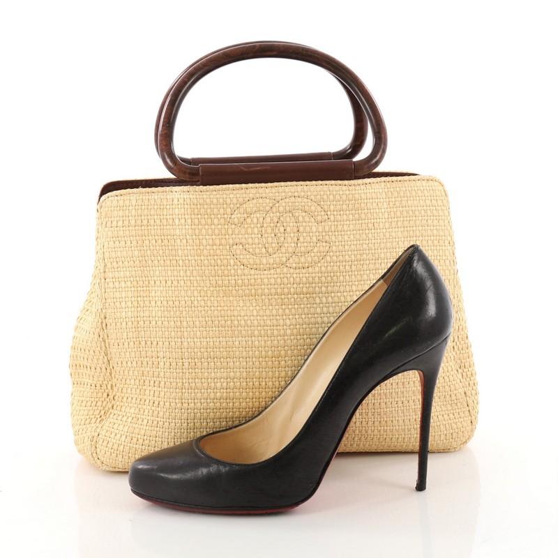 This authentic Chanel Vintage Wooden Ring Tote Woven Raffia Medium is the perfect casual companion for the modern woman. Crafted in brown woven raffia, this simple yet elegant tote features dual round wood handles, stitched CC logo at front and