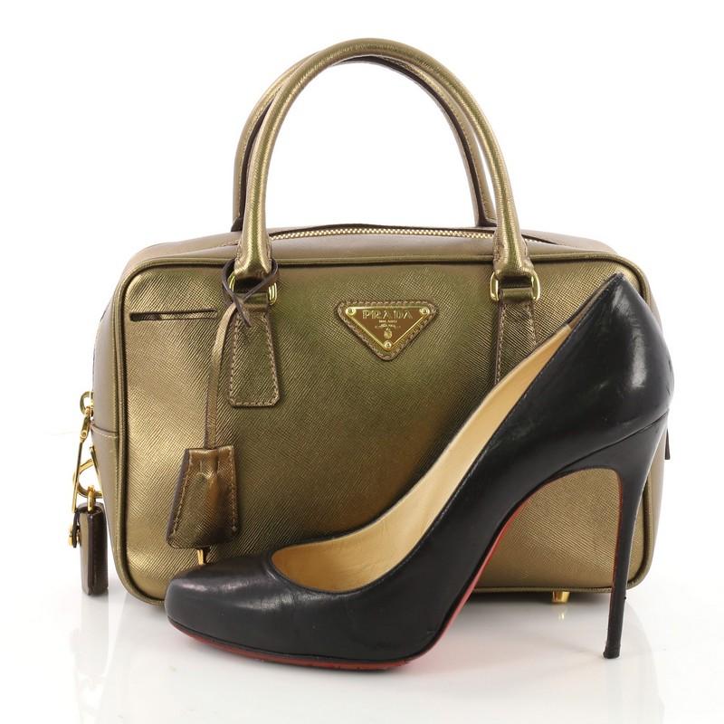 This authentic Prada Bauletto Handbag Saffiano Leather Small exudes a stylish and industrial design made for everyday excursions. Crafted from beautiful gold saffiano leather, this everyday satchel features dual-rolled tall handles, raised Prada