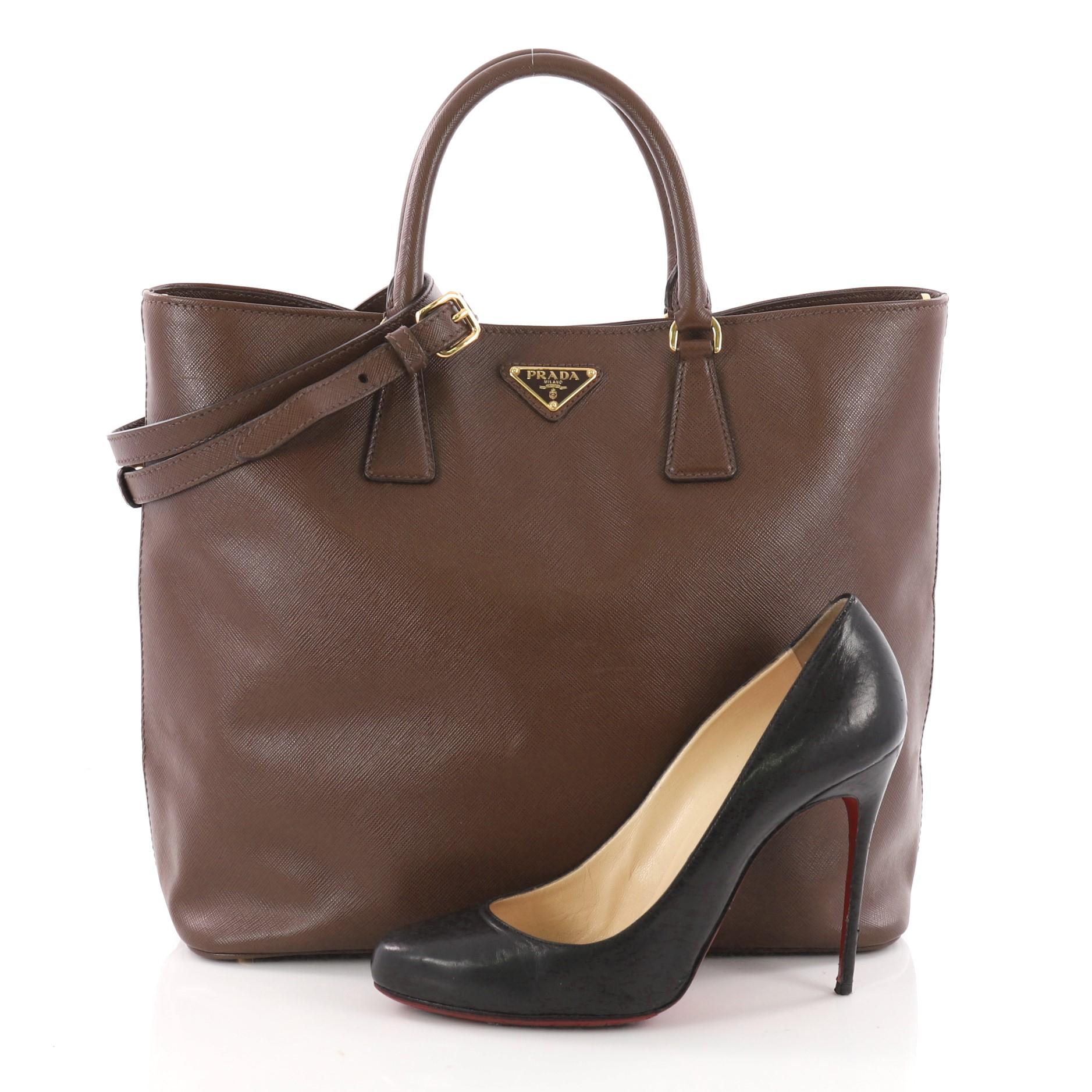 This authentic Prada Convertible Open Tote Saffiano Leather Medium is elegant in its simplicity and structure. Crafted in brown saffiano leather, this stylish yet functional tote features dual-top handles, protective base studs, signature raised