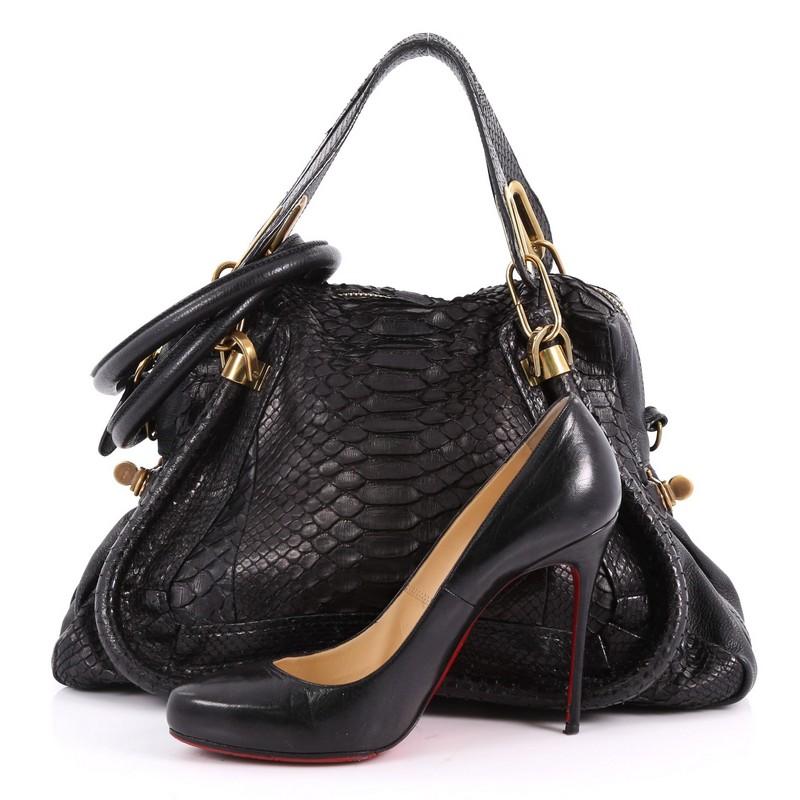 This authentic Chloe Paraty Top Handle Bag Python Medium mixes everyday style and functionality. Crafted from genuine black python skin, this versatile bag features dual flat handles, piped trim details, side twist locks, and brass-tone hardware