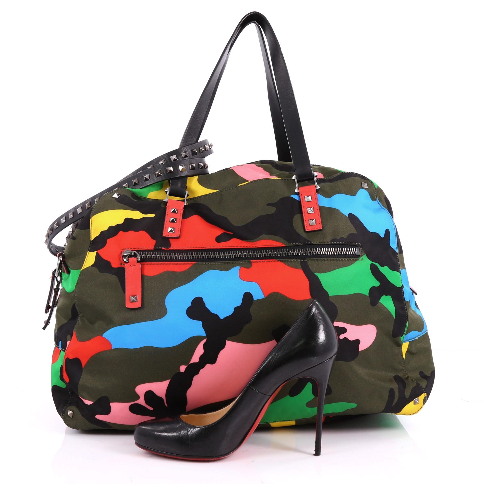 This authentic Valentino Rockstud Holdall Duffle Bag Camo Nylon Large showcases a stylishly edgy design with an easy-going silhouette. Crafted from multicolor-camo nylon, this stylish duffle bag features dual flat leather handles with rock stud