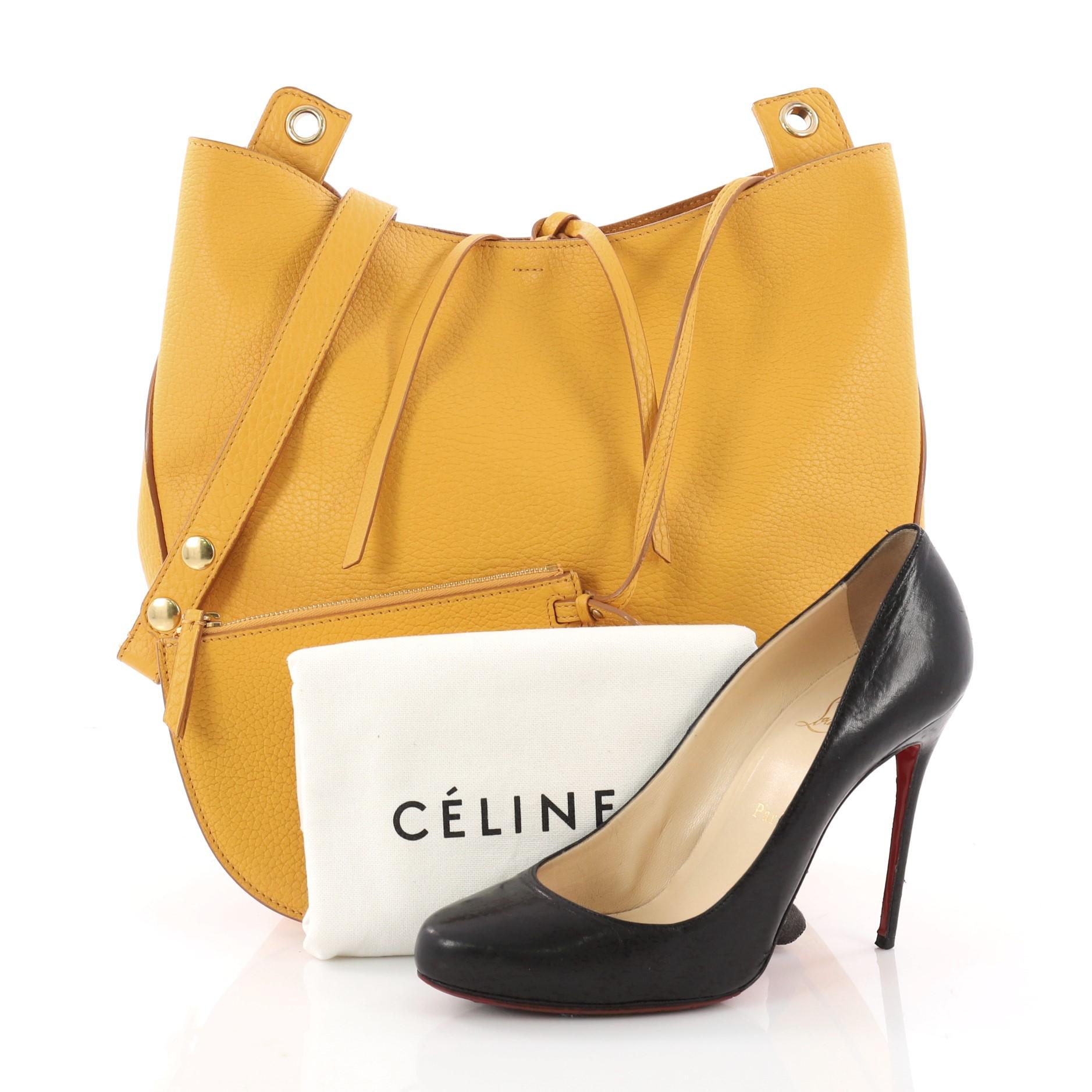 This authentic Celine Hobo Leather Medium mixes simple style with luxurious craftsmanship. Crafted from supple yellow leather, this modern hobo features a single adjustable shoulder strap, stamped Celine logo, and gold-tone hardware accent. Its top