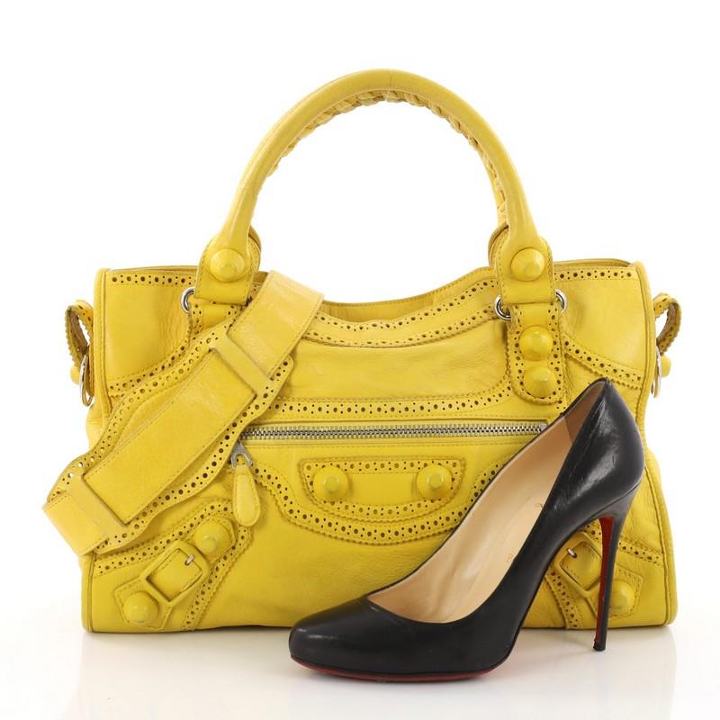 This authentic Balenciaga City Giant Brogues Medium Leather Handbag  is for the on-the-go fashionista. Constructed in yellow leather, this popular bag features braided woven handles, leather perforated trim, front zip pocket, silver-tone hardware