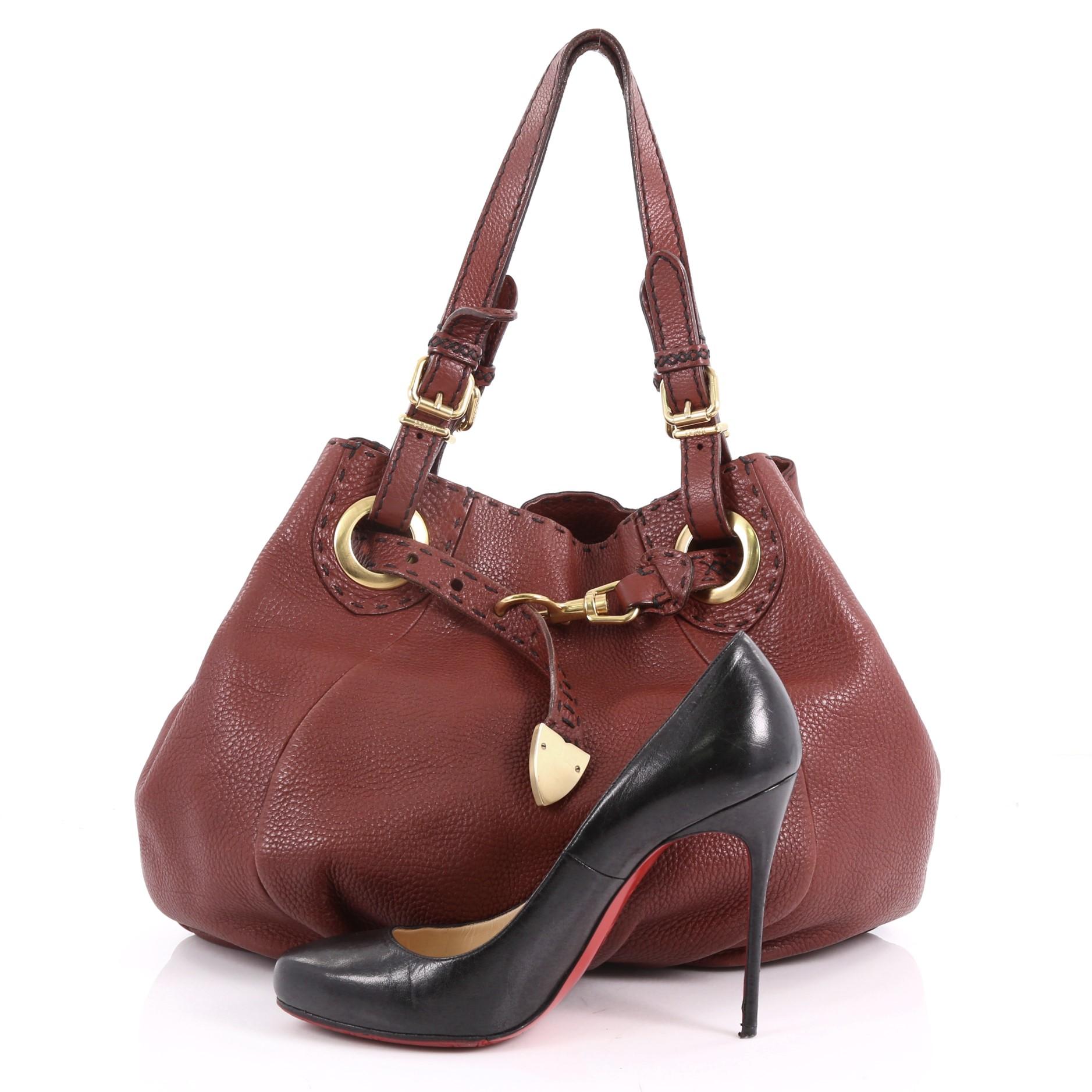 This authentic Fendi Selleria Pomodorino Bag Leather is a chic and gorgeous bag that your can wear on a daily basis. Crafted from red brown selleria leather, this bag features dual flat adjustable straps with buckle details, ruched chic silhouette