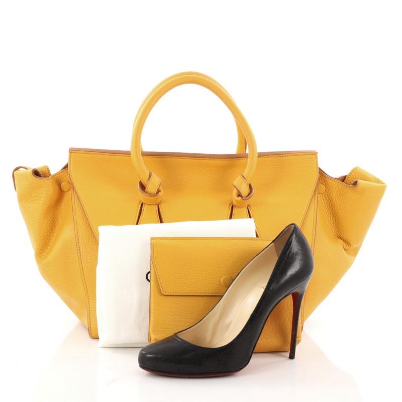 This authentic Celine Tie Knot Tote Grainy Leather Small is an absolute must-have for serious fashionistas. Crafted from yellow grainy leather, this boxy chic tote features dual-rolled leather handles with signature knot accents, protective base