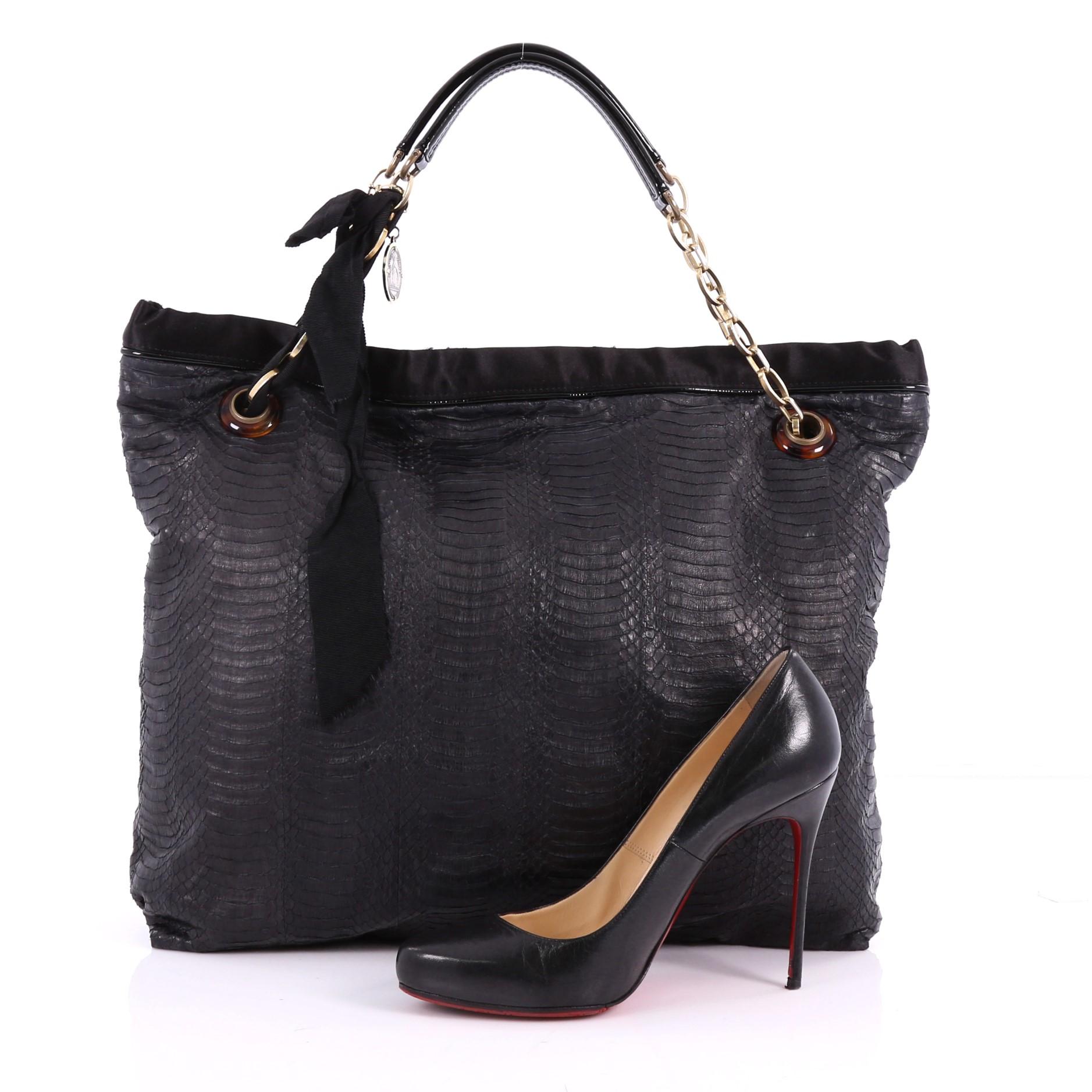 This authentic Lanvin Amalia Cabas Tote Python Large is feminine in design and ideal for everyday use. Crafted from genuine black python, this classic, oversized tote features polished chain straps with a matching tied ribbon design and charm,