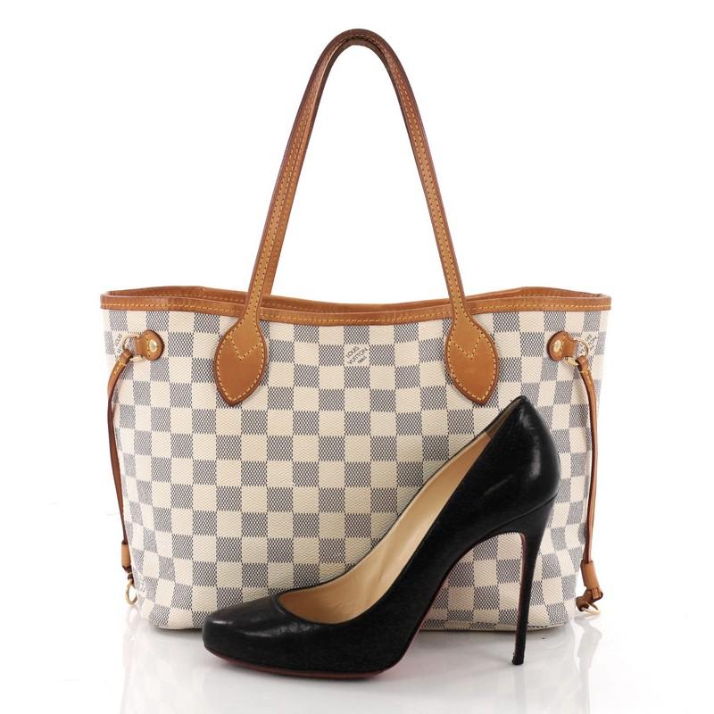 This authentic Louis Vuitton Neverfull Tote Damier PM is a popular and practical tote beloved by many. Constructed with damier azur coated canvas, this tote features dual slim vachetta leather handles, side laces that can be cinched to transform