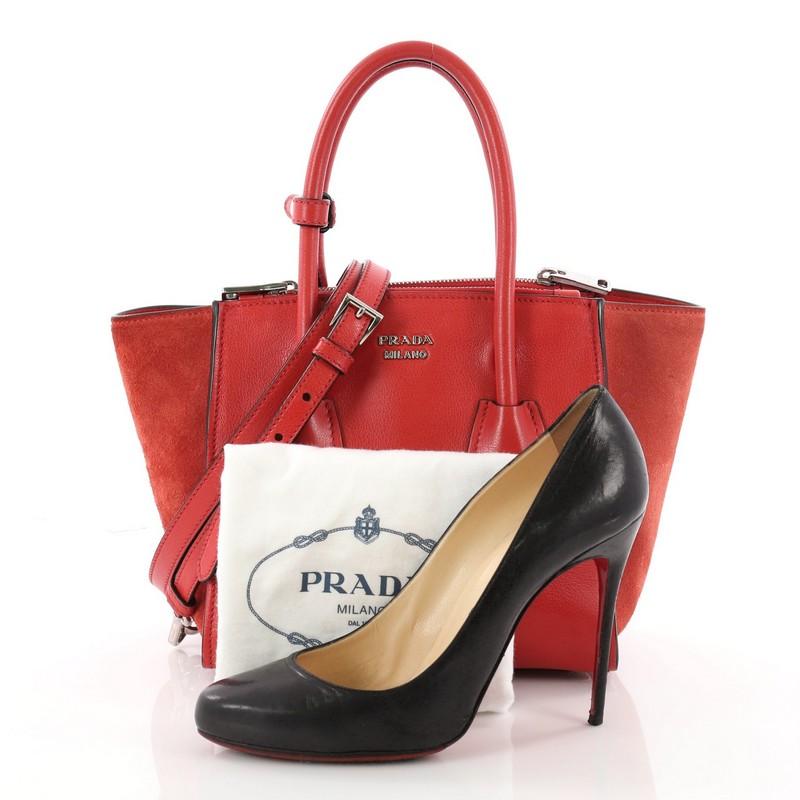 This authentic Prada Twin Pocket Tote Glace Calf and Suede Mini showcases a sophisticated silhouette. Crafted from red glace calf leather and suede, this boxy tote features tall dual-rolled top handles, signature center Prada logo, protective base