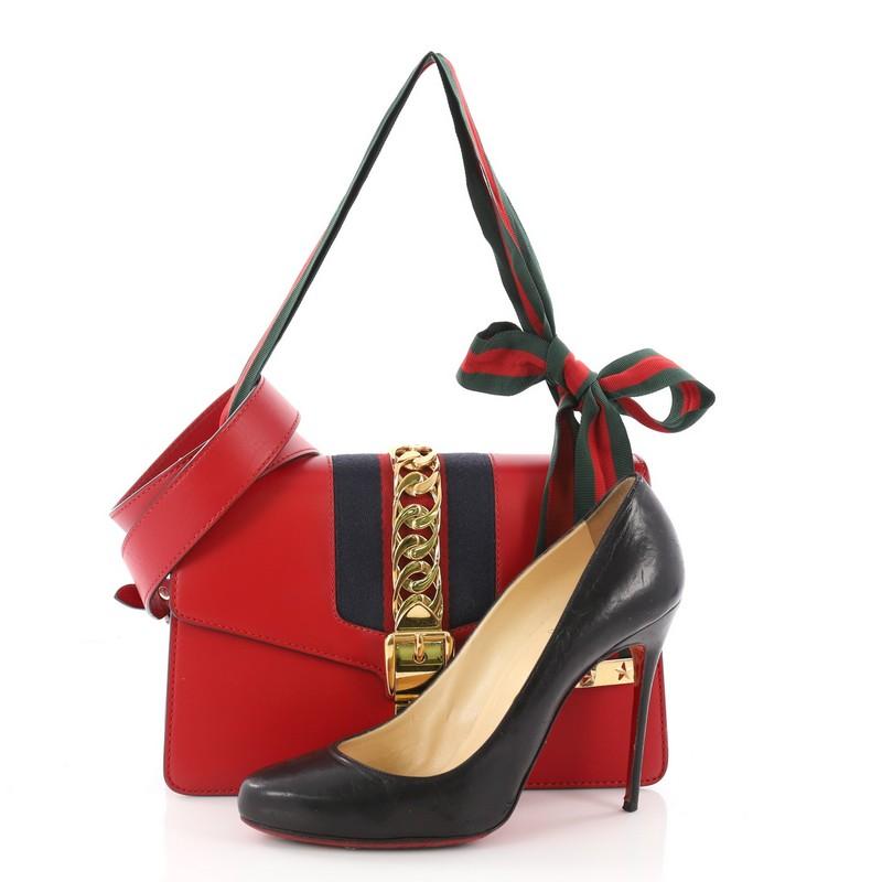 This authentic Gucci Sylvie Shoulder Bag Leather Small is perfect for the modern fashionista. Crafted from red leather, this structured bag features leather shoulder strap, nylon Web detail with curb chain and buckle closure and gold-tone hardware