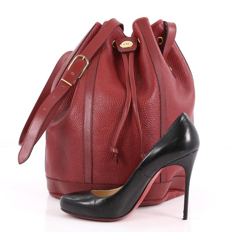 This authentic Christian Dior Vintage Drawstring Bucket Bag Leather Medium is a classic staple that every fashionista needs in her wardrobe. Crafted from red leather, this chic bucket bag features adjustable leather straps, drawstring closure